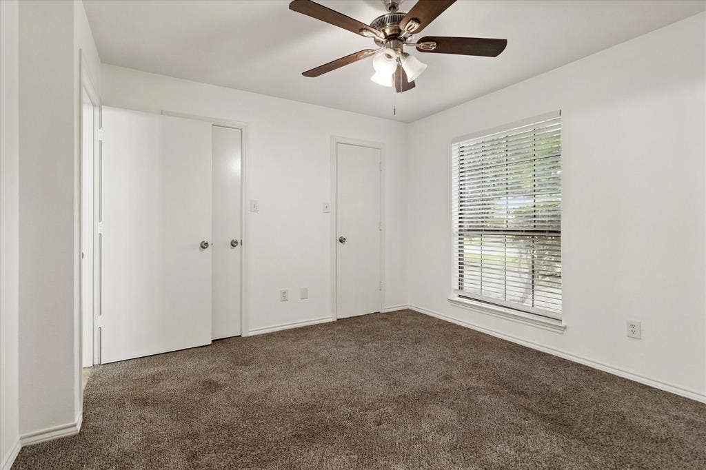 3318 Wells Drive, Plano, TX 75093 Carpeted interior space featuring a ceiling fan with integrated lighting, a window with horizontal blinds, and white interior doors with round knob hardware