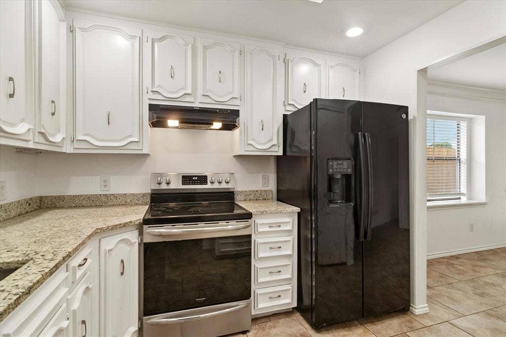 3318 Wells Drive, Plano, TX 75093 Kitchen featuring white cabinetry, light-toned countertops, a stainless steel range with an overhead vent, and a black side-by-side refrigerator