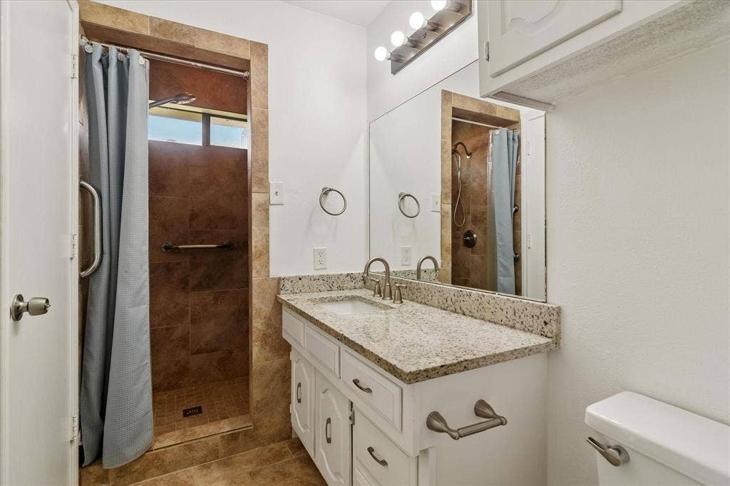 3318 Wells Drive, Plano, TX 75093 Bathroom featuring a white vanity with a speckled countertop, undermount sink, and brushed nickel faucet