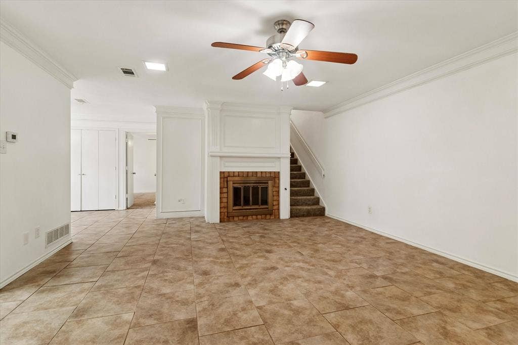 3318 Wells Drive, Plano, TX 75093 Spacious living area featuring neutral tile flooring, a wood-burning fireplace with brick surround, and a ceiling fan with integrated lighting