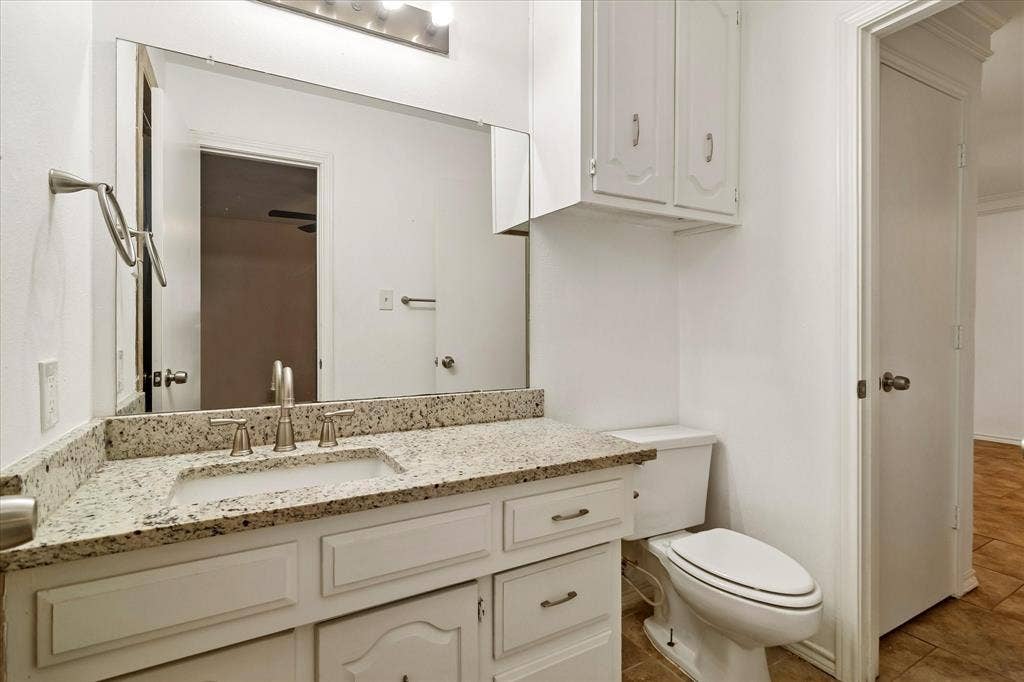 3318 Wells Drive, Plano, TX 75093 Bathroom featuring a white vanity with recessed panel cabinetry, a light speckled countertop, an undermount sink, and a large wall-mounted mirror
