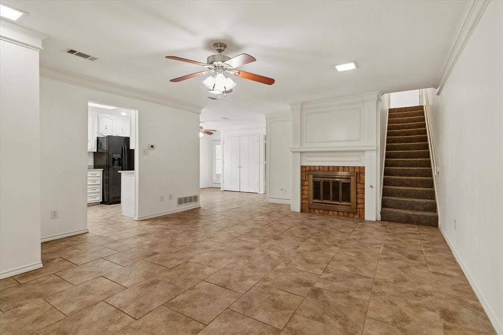 3318 Wells Drive, Plano, TX 75093 Open-concept living space featuring large format tile flooring, a white-painted fireplace with brick surround, and a ceiling fan