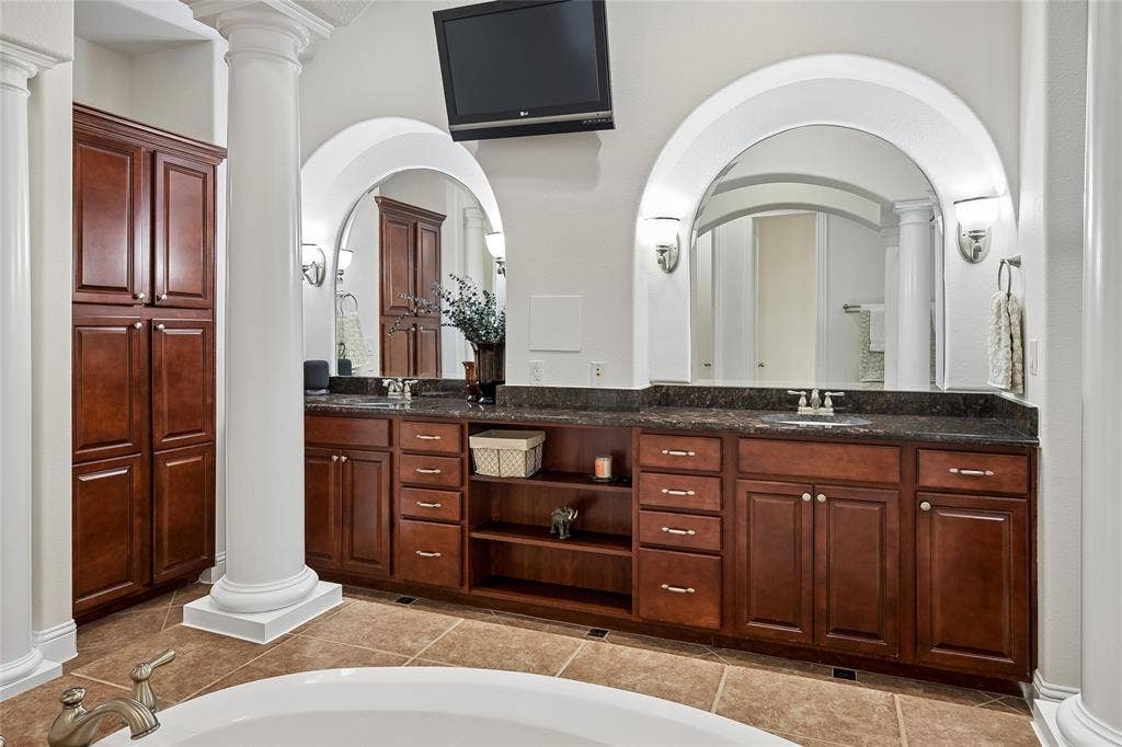 The vanity area is beautifully illuminated and provides plenty of cabinets.