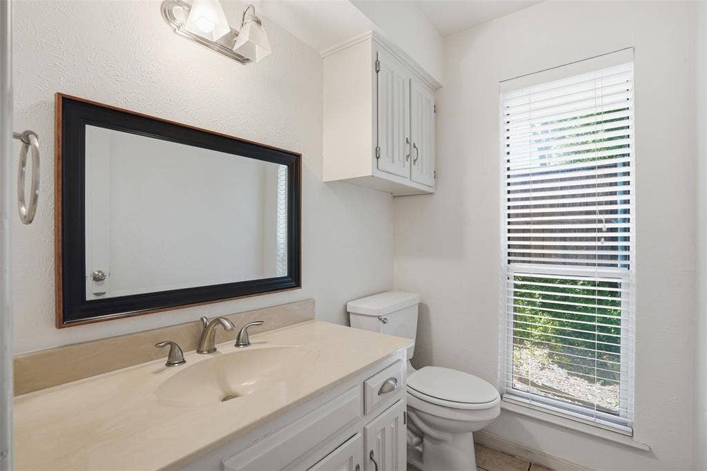 1000 Lexington Drive, Plano, TX 75075 Bathroom featuring a single vanity with an integrated sink, framed mirror, and chrome fixtures