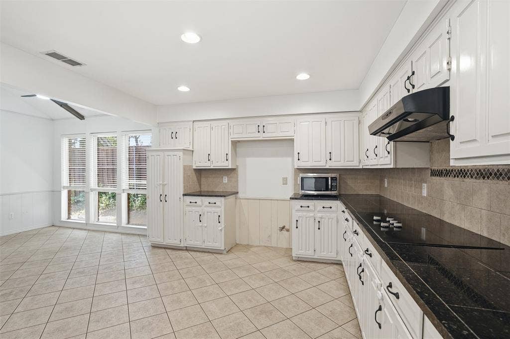 1000 Lexington Drive, Plano, TX 75075 Kitchen featuring white cabinetry, black stone countertops, and a tiled backsplash