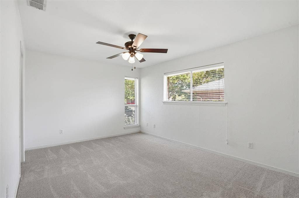 1000 Lexington Drive, Plano, TX 75075 Spacious room with light gray carpeting, neutral white walls, a ceiling fan with integrated lighting, and two windows with blinds