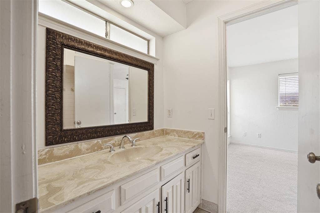 1000 Lexington Drive, Plano, TX 75075 Bathroom vanity featuring a single integrated sink, stone-finish countertop, and white cabinetry with dark hardware