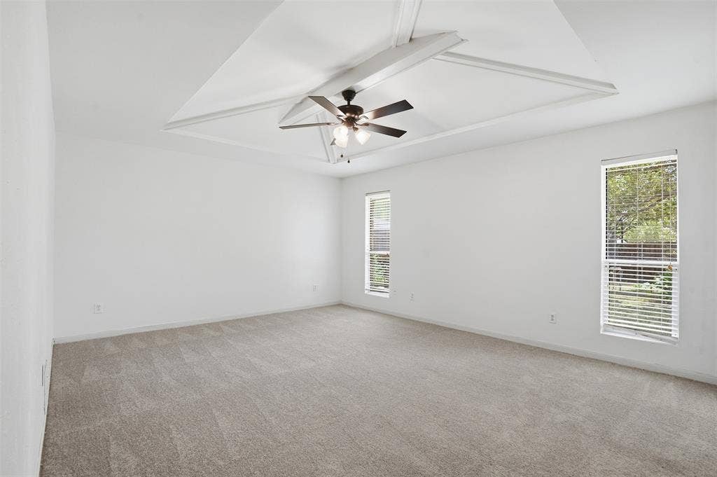 1000 Lexington Drive, Plano, TX 75075 Spacious room featuring a tray ceiling with crown molding, a ceiling fan, plush carpet flooring, and two vertical windows with blinds