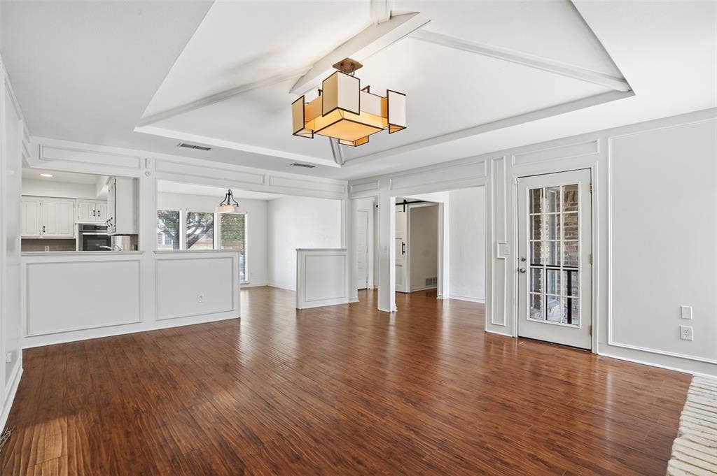 1000 Lexington Drive, Plano, TX 75075 Open concept living area featuring wood-finish flooring, a tray ceiling with exposed beams, and a modern rectangular chandelier