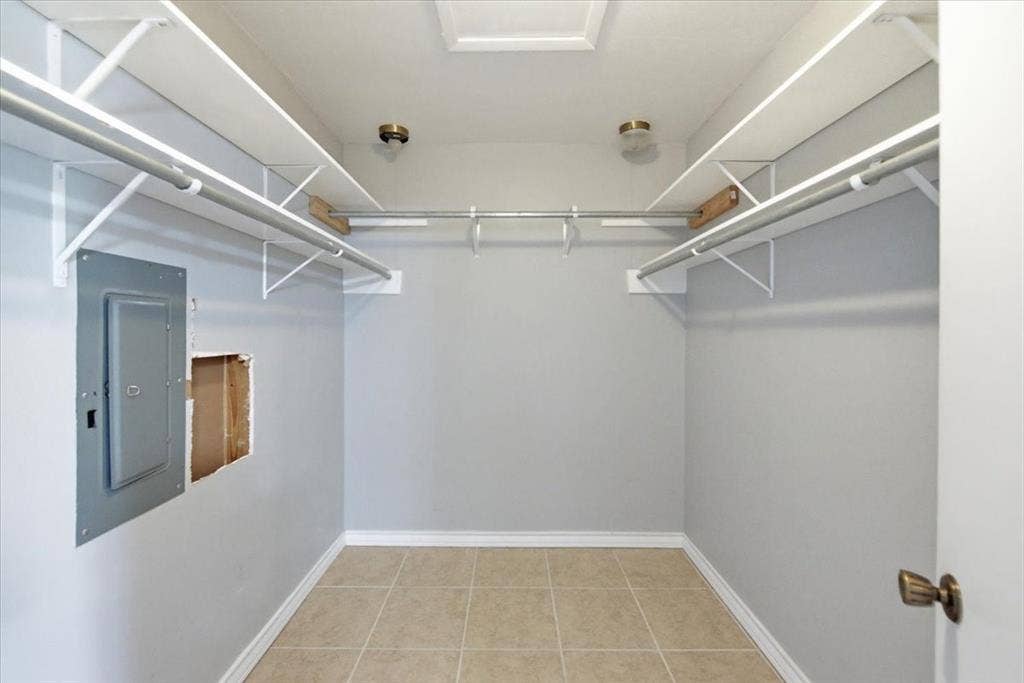 612 W Highland Street, West, TX 76691 Primary bedroom featuring a large and very functional walk-in closet with shelving and hanging rods, neutral wall color, and tile flooring
