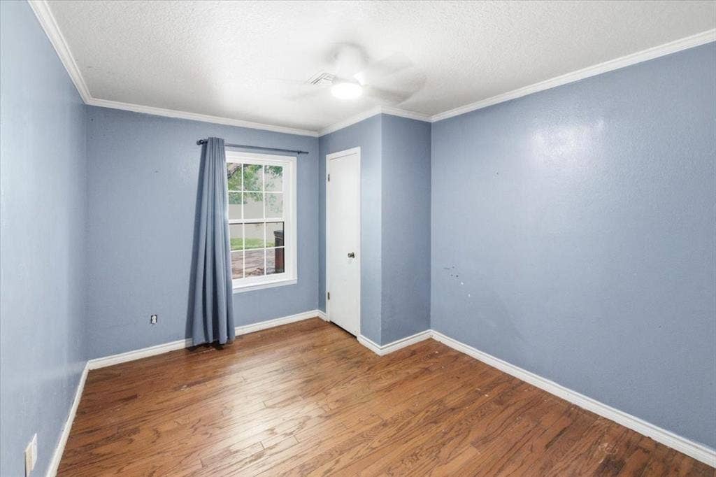 612 W Highland Street, West, TX 76691 Secondary bedroom featuring wood-finish flooring, a window with ample natural light, and a ceiling fan with integrated lighting