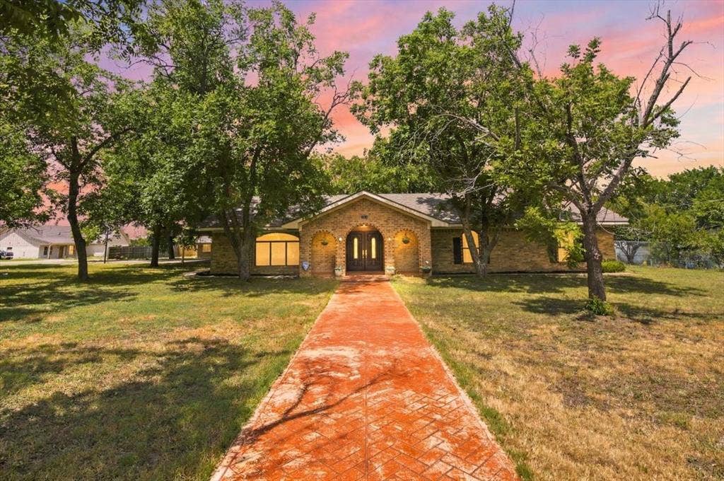 612 W Highland Street, West, TX 76691 Brick home seen from the circle driveway featuring an arched entryway, double front doors, an arched window, and a patterned walkway