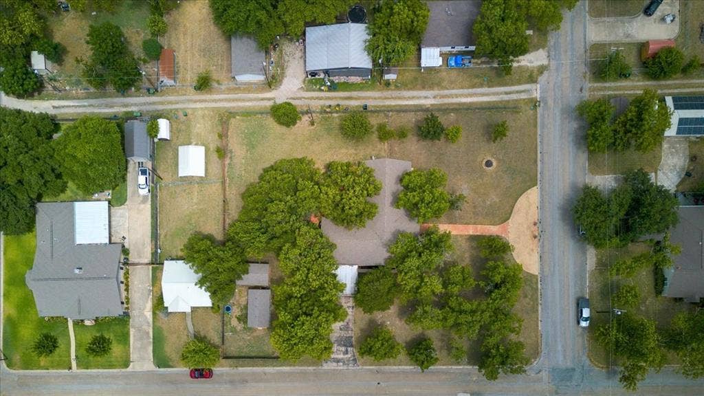612 W Highland Street, West, TX 76691 Expansive property featuring a central residence, mature trees, an extended driveway, and multiple outbuildings