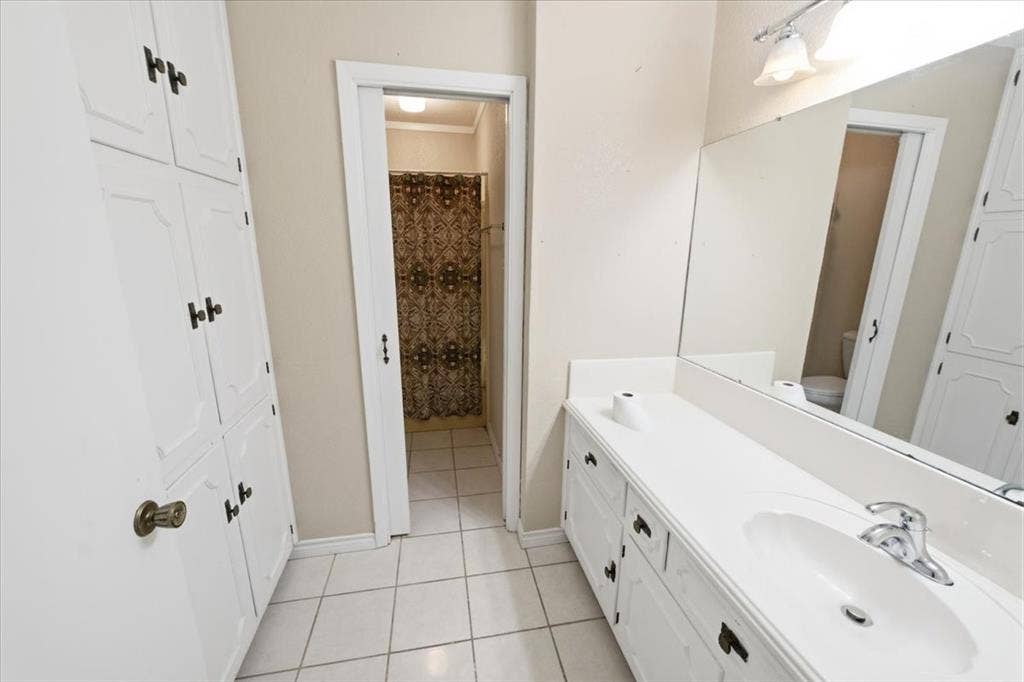 612 W Highland Street, West, TX 76691 Hall full-bathroom featuring a vanity with an integrated sink, built-in cabinetry, toilet, and a tub & shower combo
