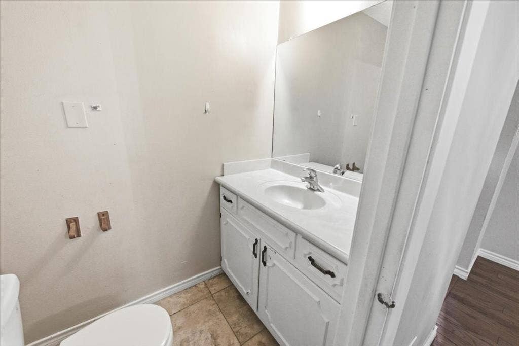 612 W Highland Street, West, TX 76691 Half-bathroom featuring a white vanity with integrated sink, a wall-mounted mirror, and tile flooring