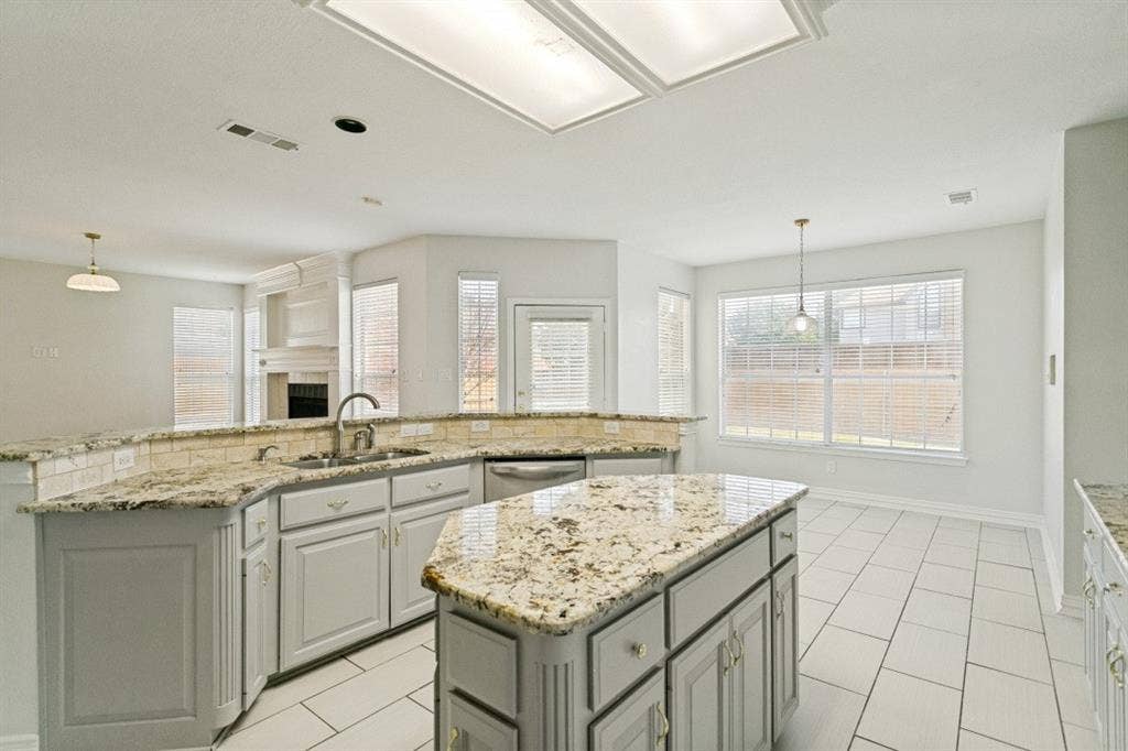 8512 Mesa Verde Drive, Plano, TX 75025 Kitchen featuring a central island with countertop, coordinating perimeter countertops with a tile backsplash, light-toned cabinetry, and stainless steel appliances