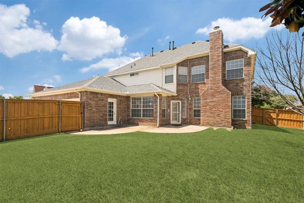 8512 Mesa Verde Drive, Plano, TX 75025 Rear exterior featuring a brick and siding facade, a large patio area, and a private fenced yard