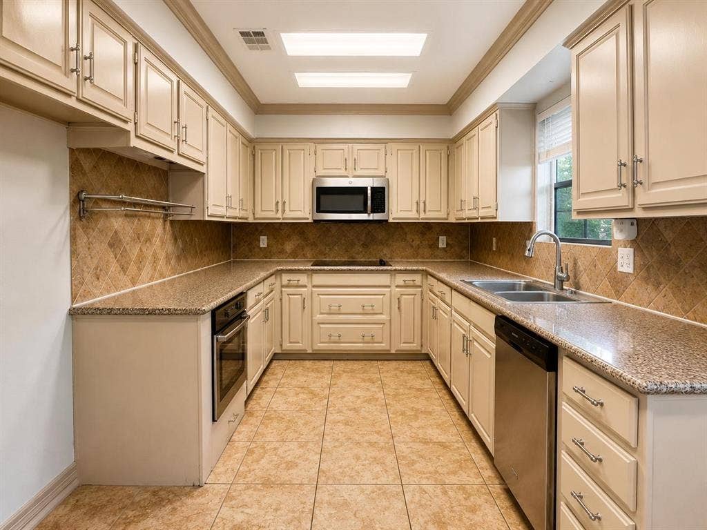 7806 Williams Avenue, Frisco, TX 75033 Kitchen featuring extensive cream cabinetry, granite countertops, and a tiled backsplash