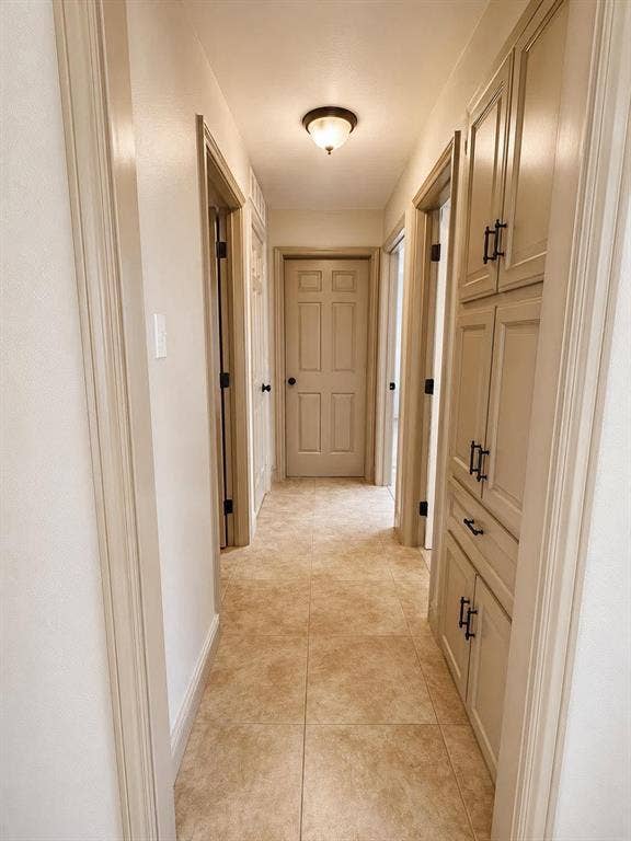 7806 Williams Avenue, Frisco, TX 75033 Hallway featuring neutral-toned tile flooring, built-in cabinetry with dark hardware, and a ceiling-mounted light fixture