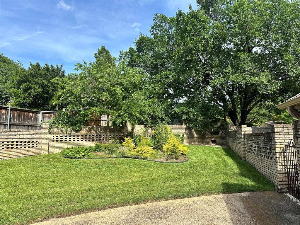 12022 Dixfield Drive, Dallas, TX 75218 Beautifully landscaped backyard with mature greenery, creating a peaceful outdoor setting.