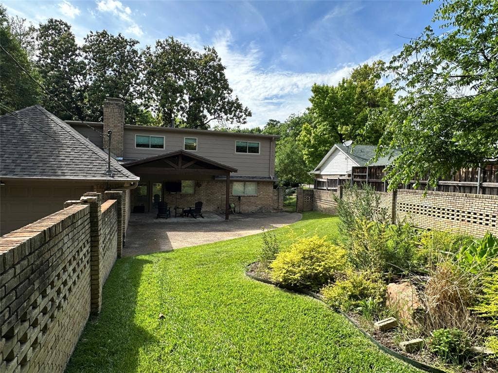 12022 Dixfield Drive, Dallas, TX 75218 Beautifully landscaped backyard with mature greenery, creating a peaceful outdoor setting for relaxing or entertaining.