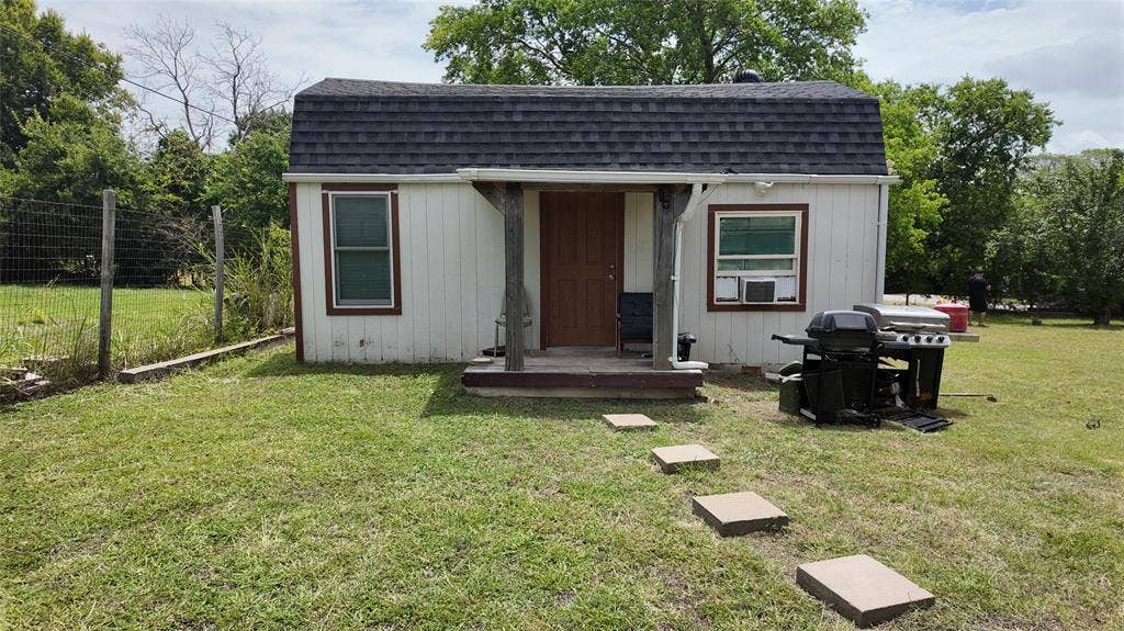 Freestanding structure featuring a gambrel roof and vinyl siding