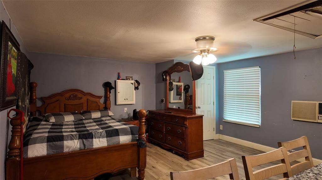 Spacious room featuring wood-finish flooring, a ceiling-mounted light fixture, and a window with horizontal blinds