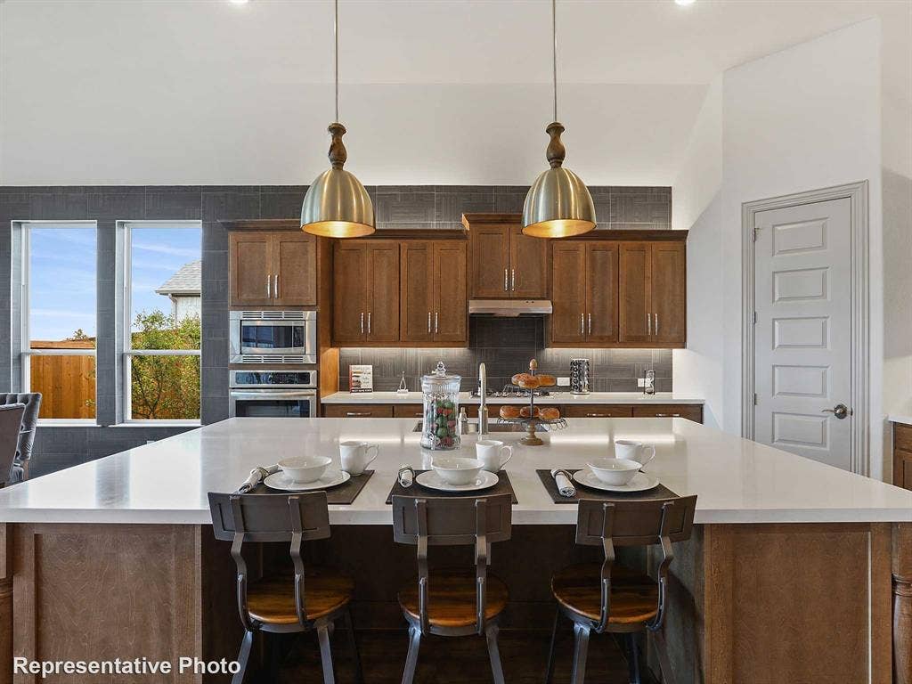 4359 Michigan Avenue, Midlothian, TX 76065 Expansive kitchen island with a light-toned countertop, rich wood-finish cabinetry, stainless steel built-in appliances, a tiled backsplash, and recessed lighting