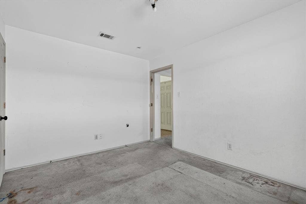 1414 Aviary Drive, DeSoto, TX 75115 White-painted interior walls with a gray carpeted floor, featuring a doorway leading to another interior space