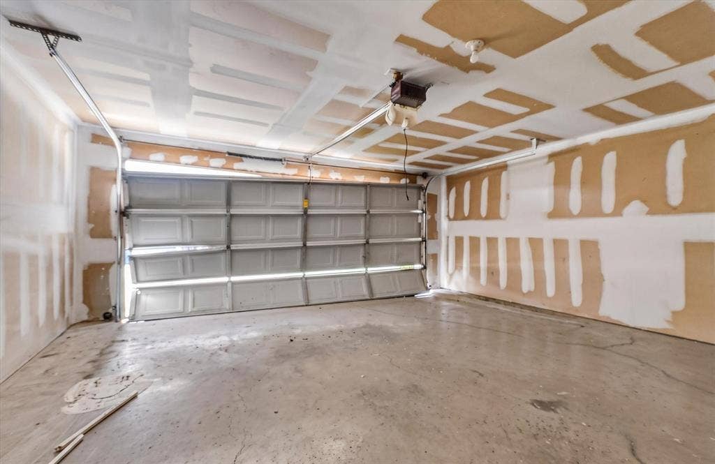 1414 Aviary Drive, DeSoto, TX 75115 Spacious garage featuring a concrete floor, an overhead garage door, and visible ceiling joists