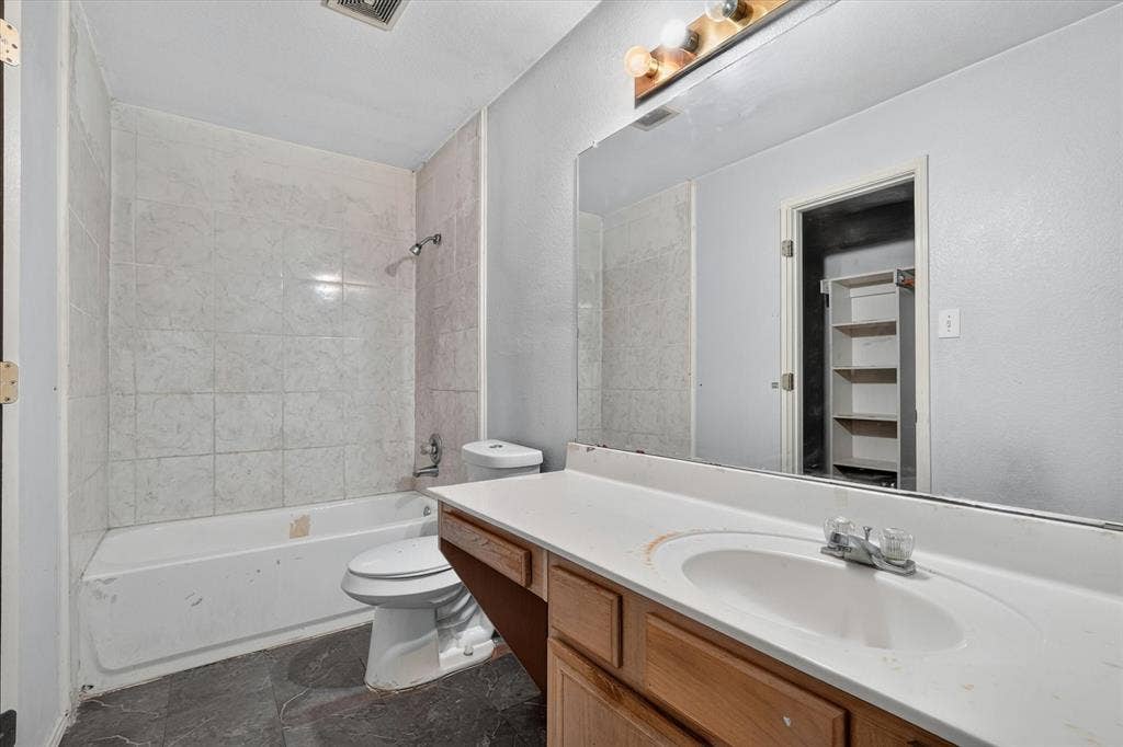 1414 Aviary Drive, DeSoto, TX 75115 Bathroom featuring a full vanity with a built-in sink and wood-finish cabinetry, a large wall-mounted mirror, and a tub-shower combination with tiled walls