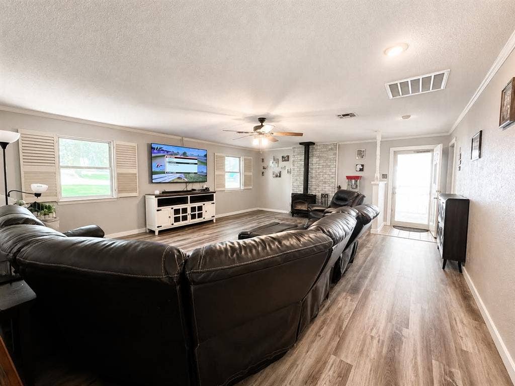 7761 Fm 2494, Athens, TX 75751 Spacious living area featuring wood-finish flooring and a wood-burning stove with a brick-style surround