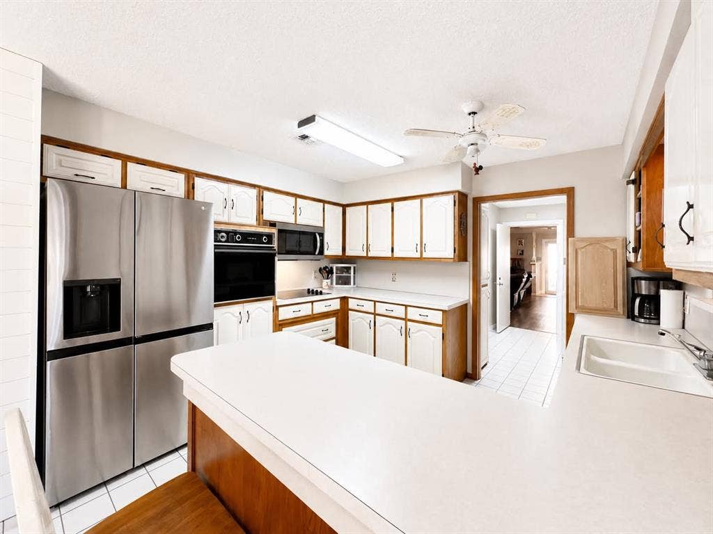 7761 Fm 2494, Athens, TX 75751 Kitchen featuring white cabinetry with wood trim, stainless steel appliances, a built-in oven, and white countertops
