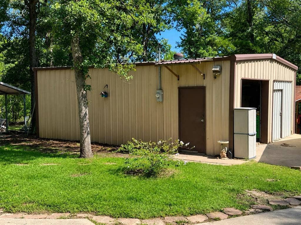 7761 Fm 2494, Athens, TX 75751 Corrugated metal building featuring a brown door, roll-up garage door, and a covered carport structure