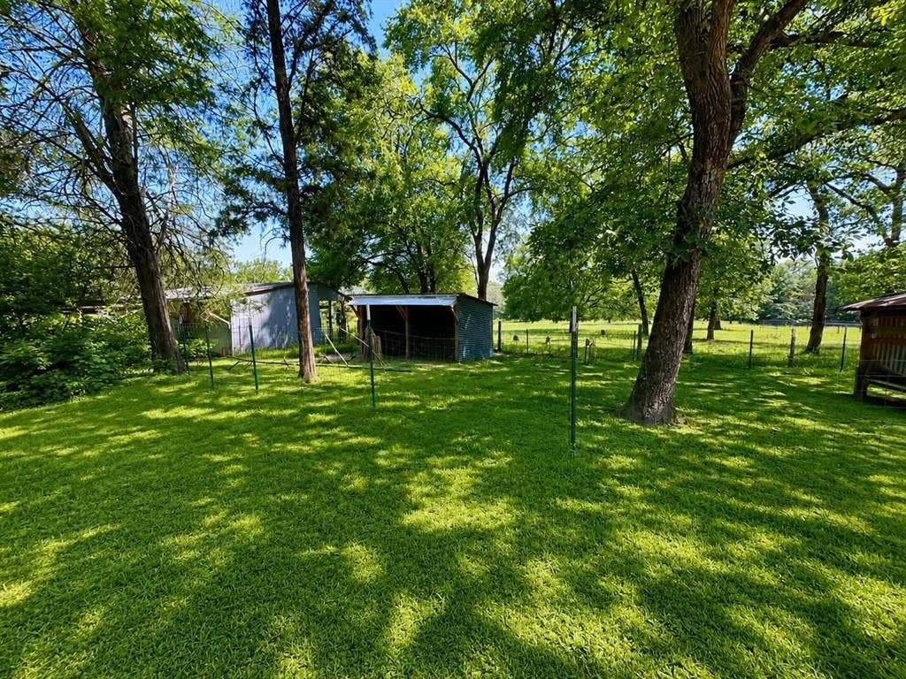 7761 Fm 2494, Athens, TX 75751 Expansive grassy area featuring mature trees, a metal shed, and a covered animal shelter