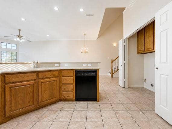 Kitchen featuring wood cabinetry, light-toned countertops, and a black dishwasher