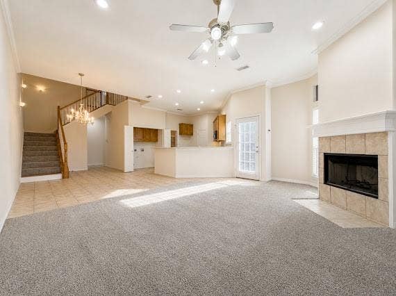 Spacious living area featuring high ceilings, light neutral-toned walls, and a tiled fireplace hearth