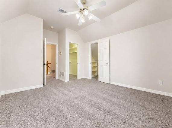 Carpeted room with vaulted ceilings and a ceiling fan