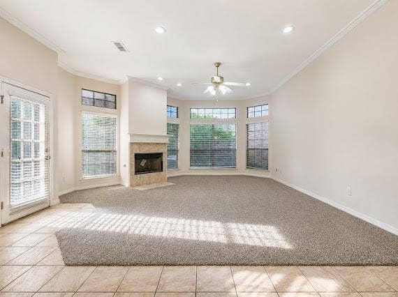 Spacious room featuring a corner fireplace with stone surround, a bay window with multiple panes, recessed lighting, and a ceiling fan