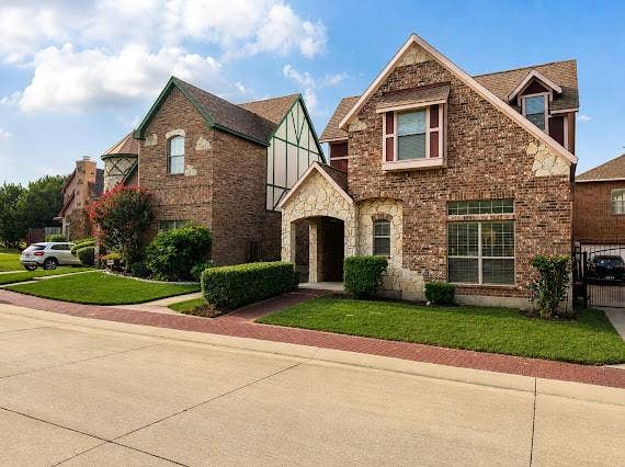 Brick and stone facade residence featuring a covered porch entry