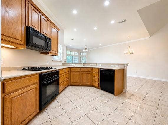 Kitchen featuring light wood cabinetry, light-toned countertops, and black appliances including a built-in microwave, gas cooktop, and oven