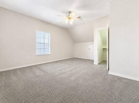 Spacious room featuring neutral carpeting, a ceiling fan, and a window with horizontal blinds