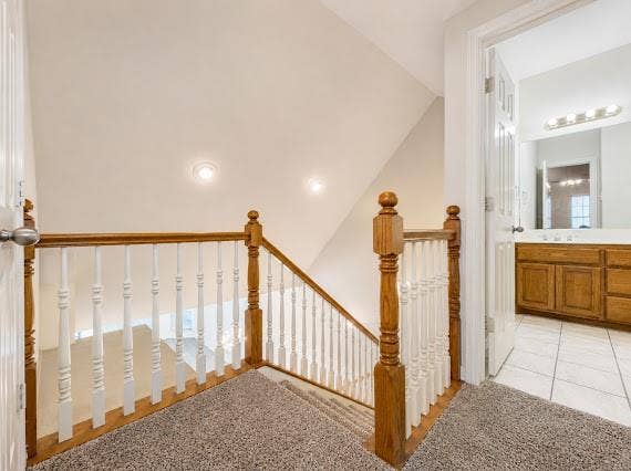 Carpeted upper landing featuring a wood and white spindle railing