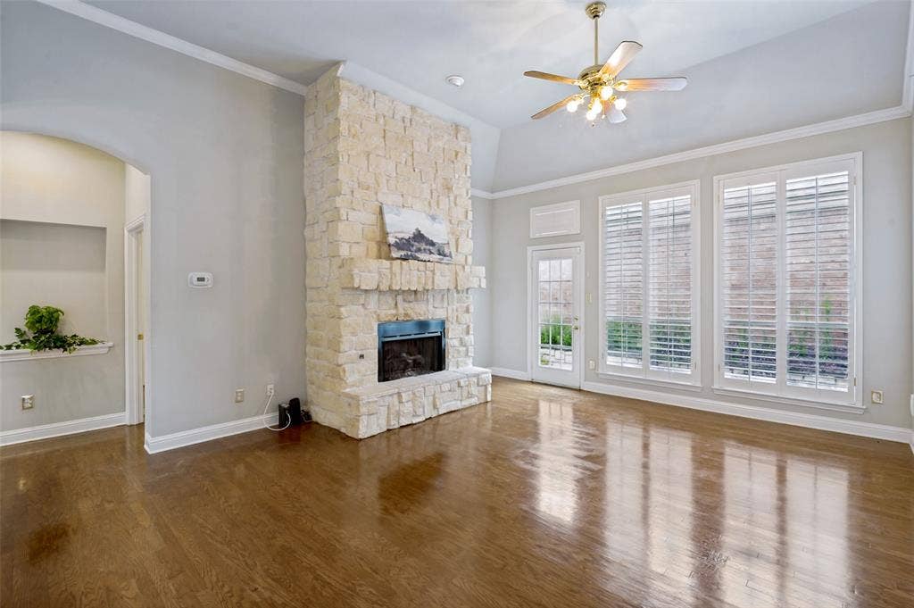 8012 Springmoss Drive, Plano, TX 75025 Spacious living area featuring a floor-to-ceiling stone fireplace, high vaulted ceilings, and rich wood-finish flooring