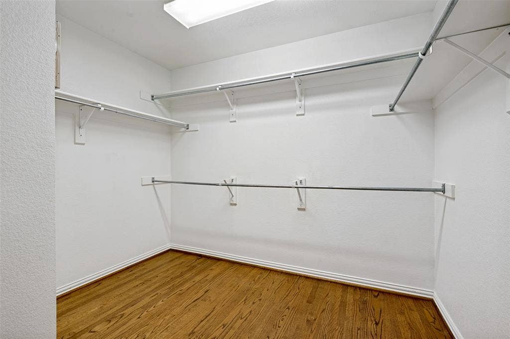 8012 Springmoss Drive, Plano, TX 75025 Spacious walk-in closet featuring wood-finish flooring and multiple shelving and hanging rods