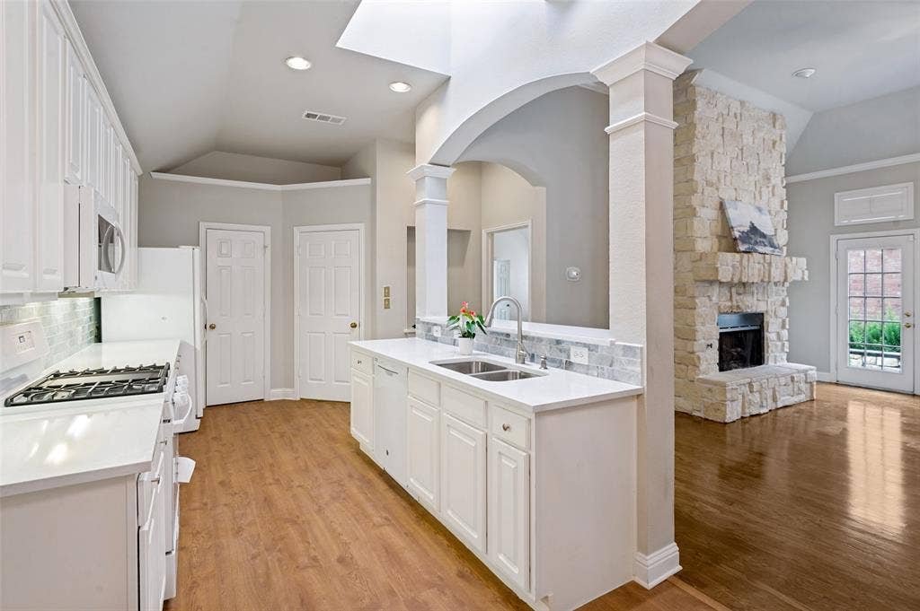 8012 Springmoss Drive, Plano, TX 75025 Open-concept kitchen featuring white cabinetry light blue backsplash, light-toned countertops, and a subway tile backsplash