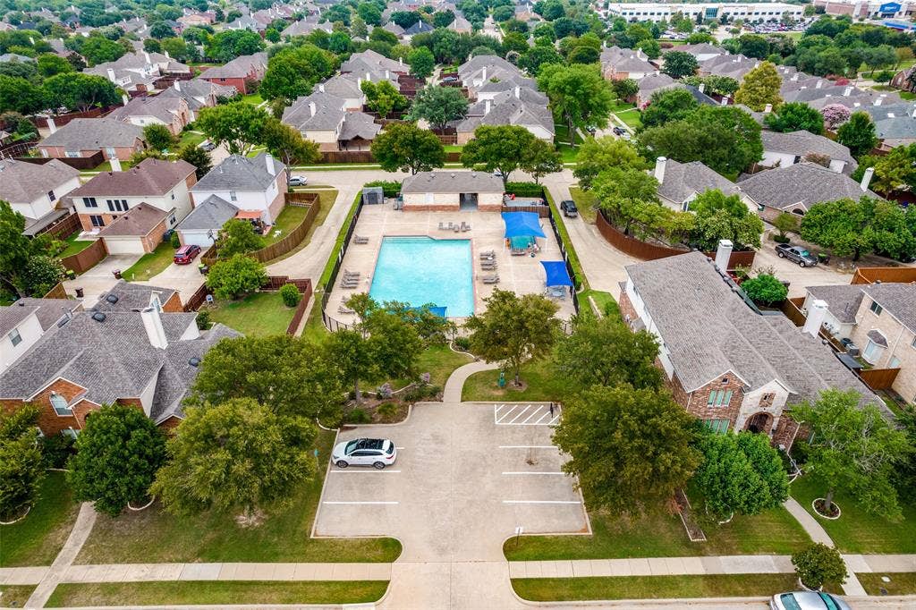 8012 Springmoss Drive, Plano, TX 75025 Community swimming pool with surrounding lounge areas and sun shades, bordered by mature trees and a dedicated parking lot