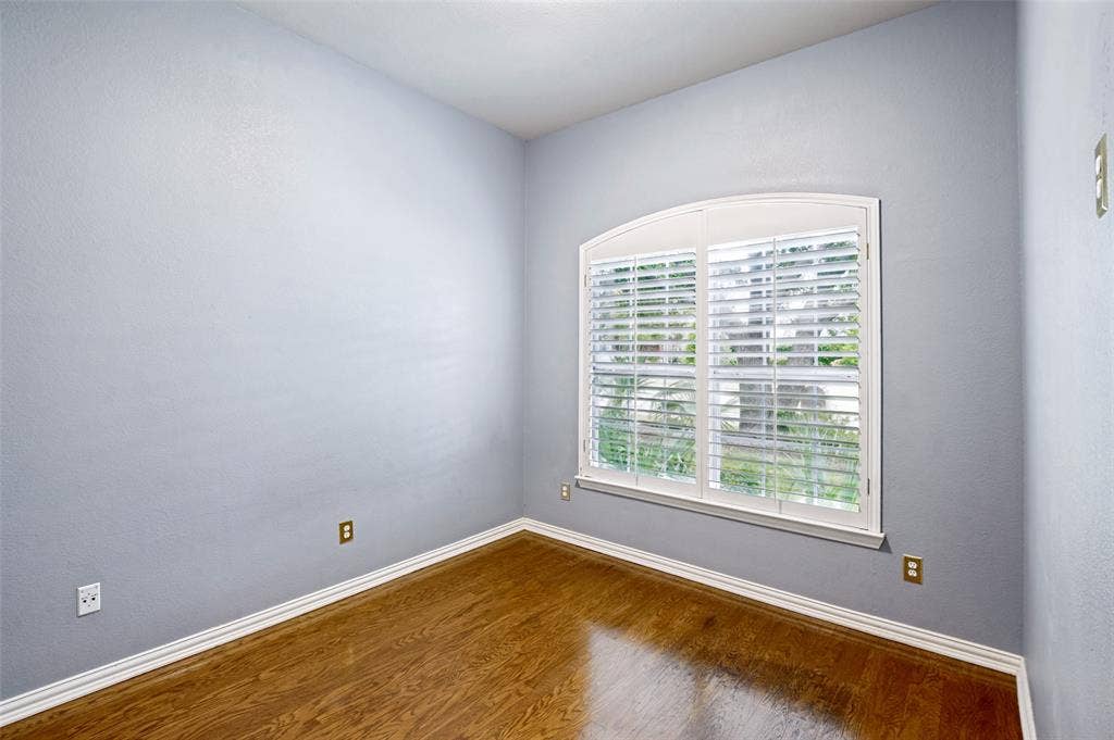 8012 Springmoss Drive, Plano, TX 75025 Room featuring wood-finish flooring, plantation shutters, light blue wall paint, and white baseboards