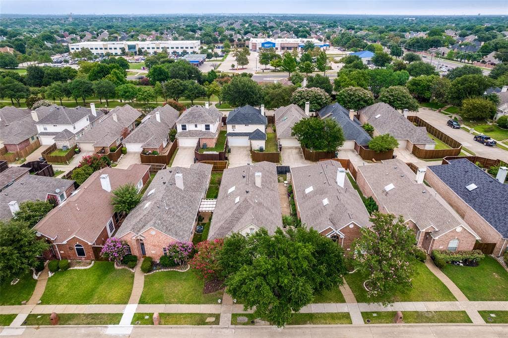 8012 Springmoss Drive, Plano, TX 75025 Aerial perspective of a residential street with an array of traditional brick and siding homes, each featuring gabled roofs and private driveways
