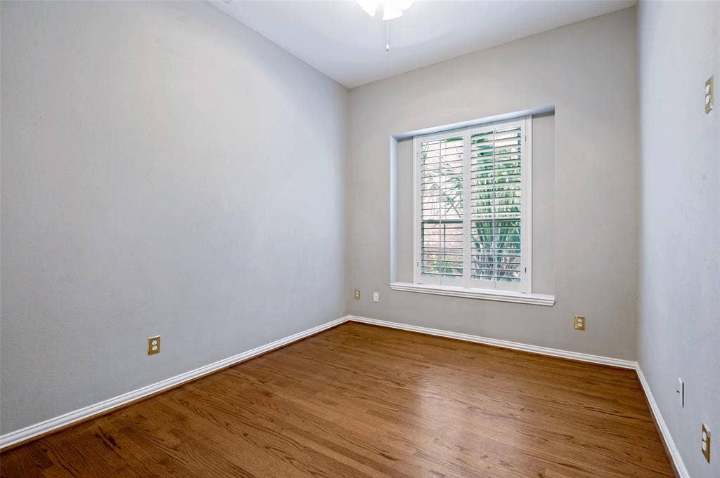 8012 Springmoss Drive, Plano, TX 75025 Room featuring wood-finish flooring, white baseboards, a window with plantation shutters, light gray wall paint, and a ceiling fan